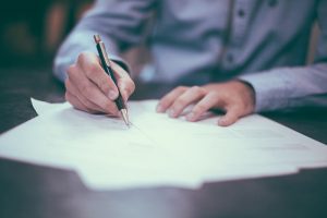 man's hands signing document with pen