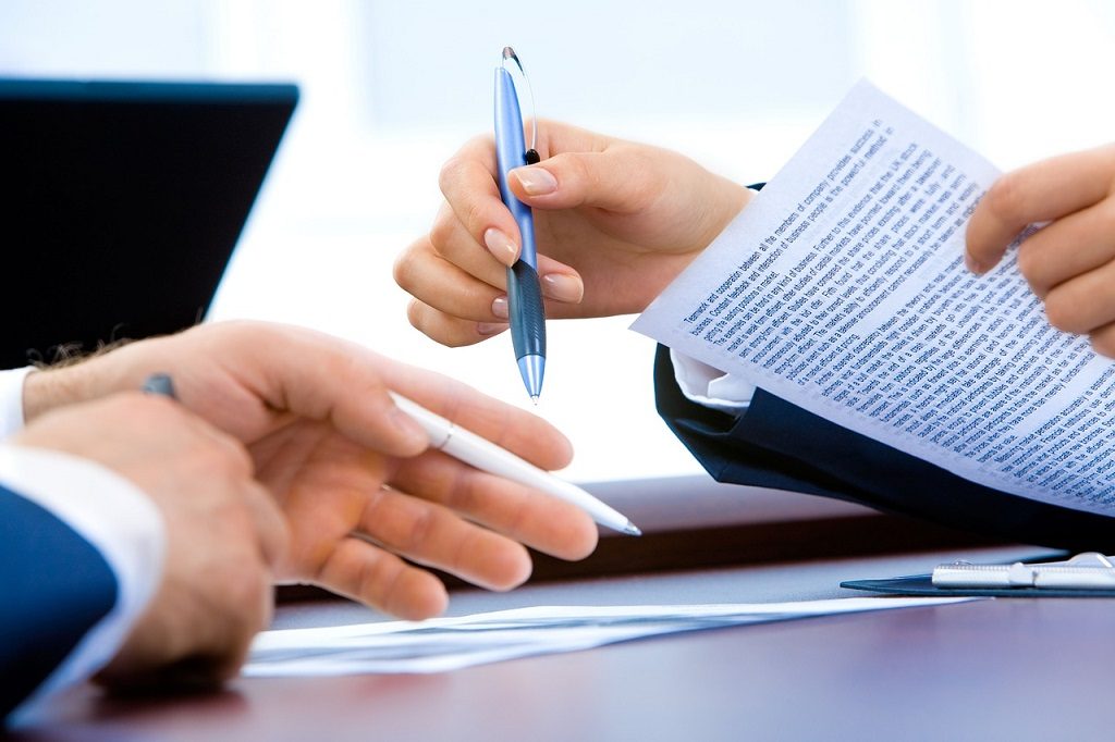 man and woman holding pens pointing at document